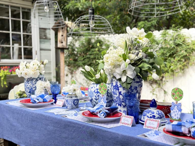 Table set for the fourth of July on the side yard. Blue table cloth with free printables decorating he table in red, white and blue.