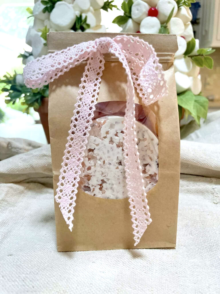A small brown bag with a window, showing homeade seasalt soap. Tied with a pink bow