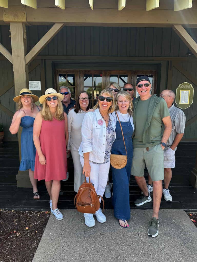 Group of gals and guys standing in a winery room 