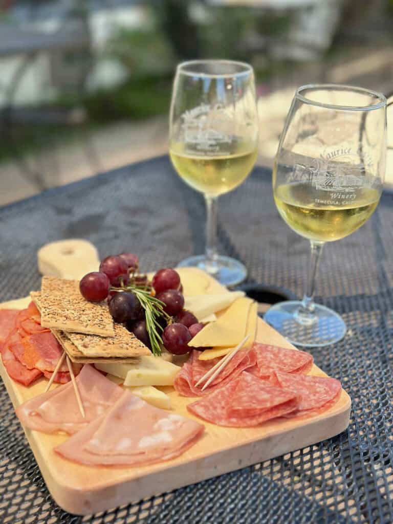 two wine glasses with a charcuterie board of salami, cheese and fruit 