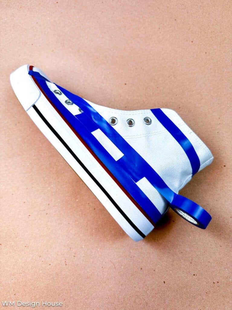 How to paint canvas shoes-A canvas shoe with tape marking the area to paint the stripes for the patriotic shoes 