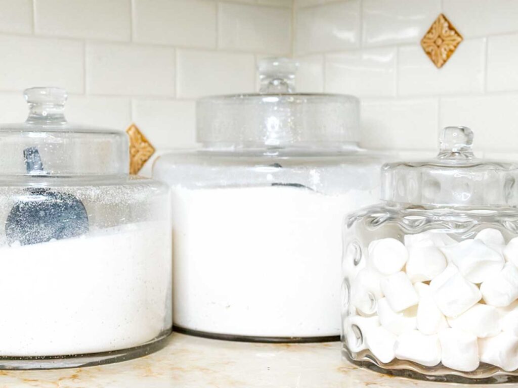 jars of flour and sugar in glass apotecary jars on the kitchen counter 