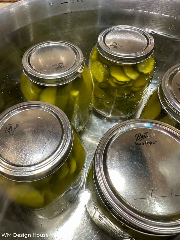 Mrs. Wages pickle mix recipe - jars of pickles sitting in a warm water bath 