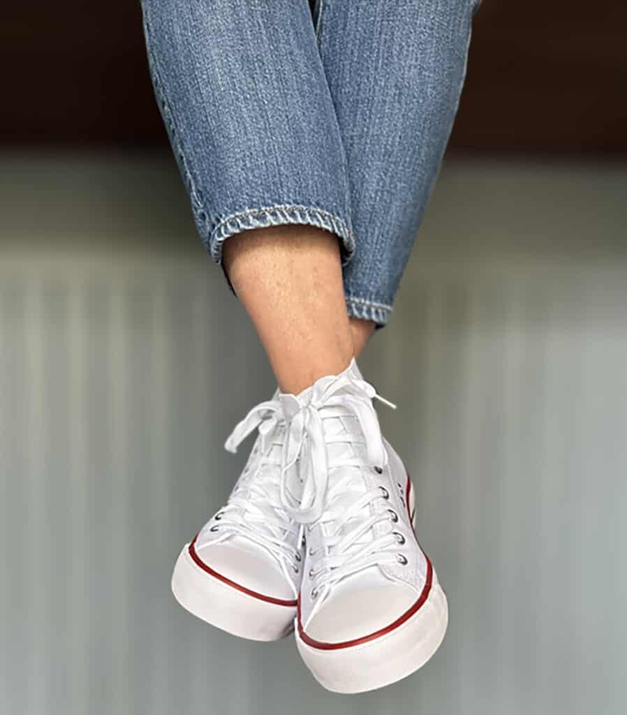White tennis shoes on a girl sitting on a counter 