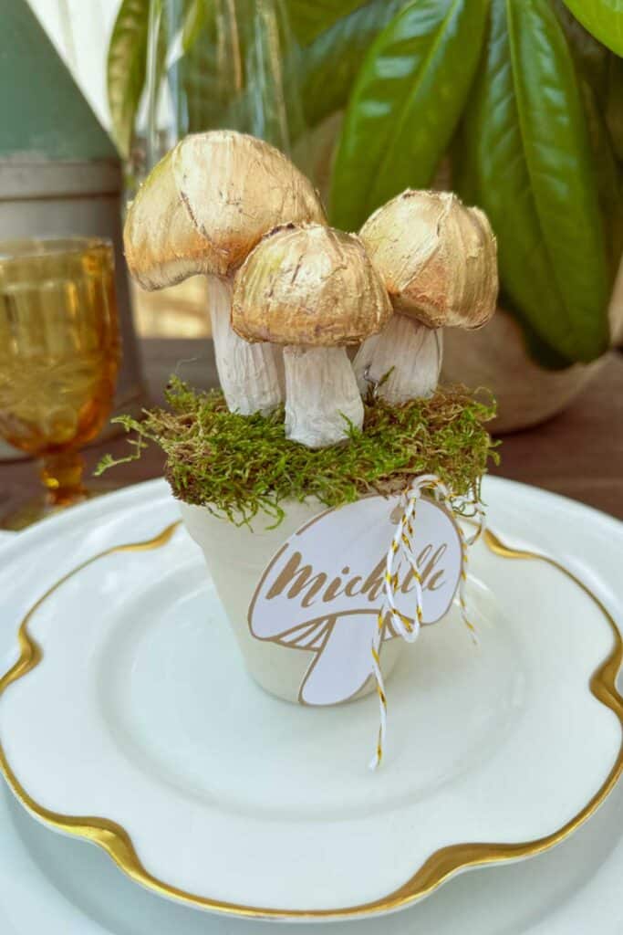 DIY Christmas Place Card Holders - three gold and white mushrooms sitting in a flower pot with a mushroom name tag for a Christmas table decoration. 