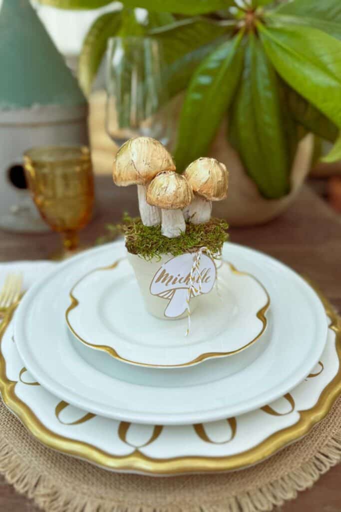 DIY Christmas Place Card Holders - three gold and white mushrooms sitting in a flower pot with a mushroom name tag for a Christmas table decoration.