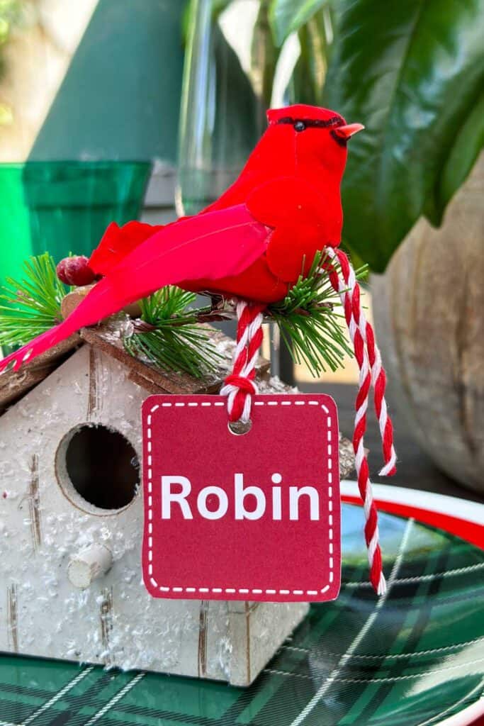 A small bird house that is  used to hold a name card at a table for Christmas. 
