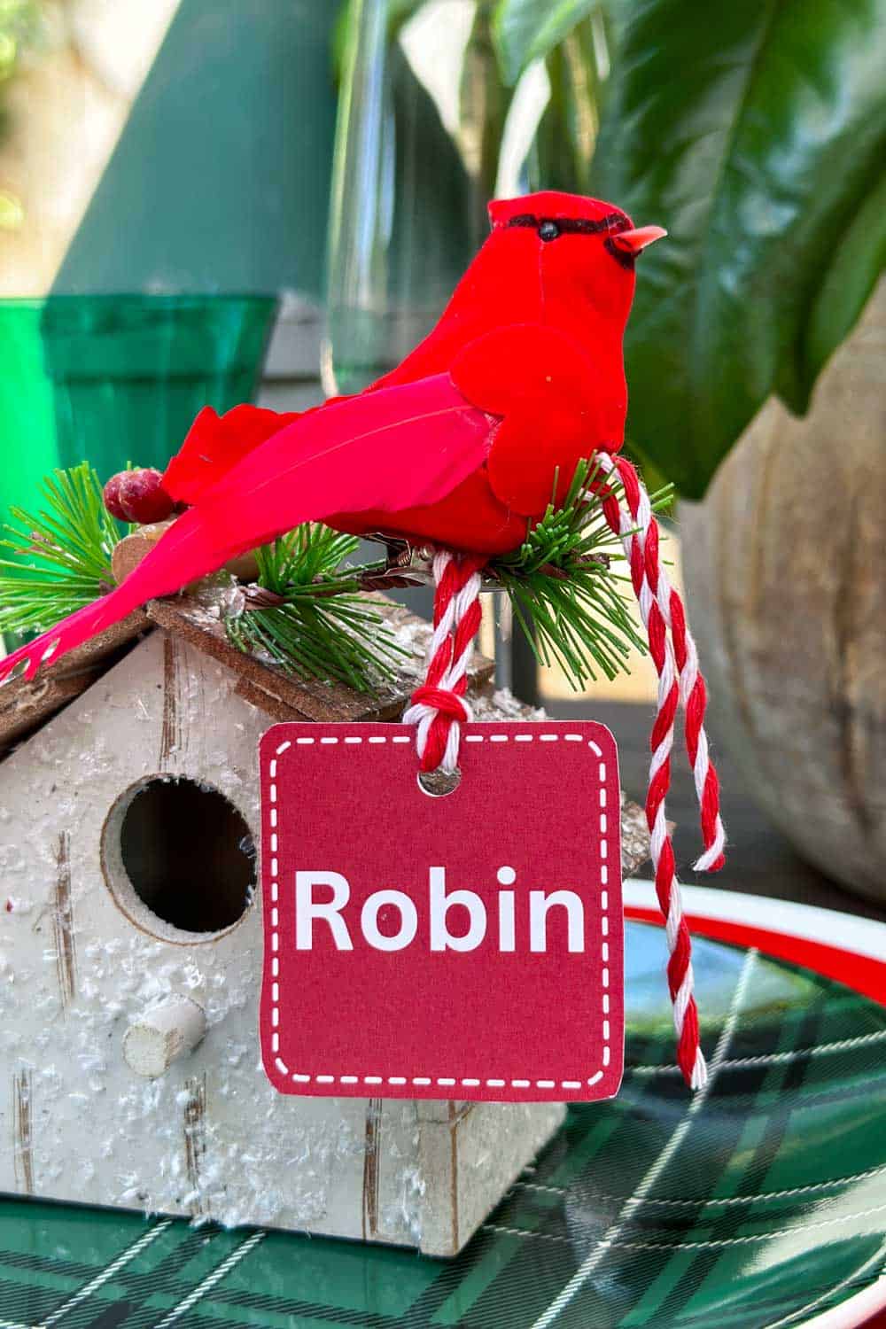 A small bird house that is used to hold a name card at a table for Christmas.