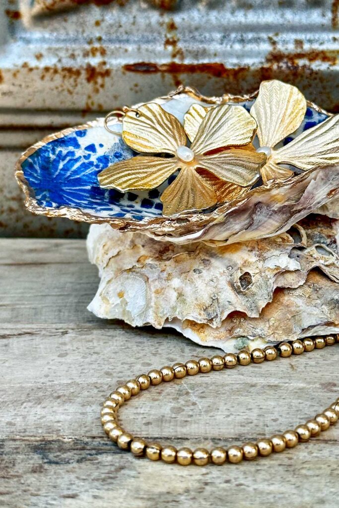 Oyster shell decoupaged  with blue and white napkin and trimmed with gold. Used as a jewelry dish. 