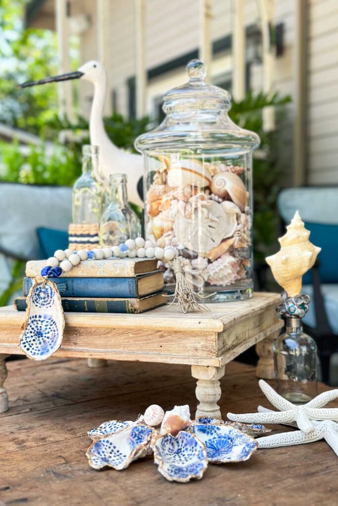How to Make a Beautiful Wood Beaded Garland with Oyster Shell-garland hanging over books in a small coastal vibe vignette