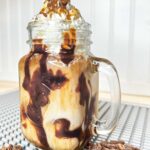 The Best Iced Mocha Macchiato Recipe: Starbucks Copycat- a delicious iced coffee drink in a mason jar with a handle topped with whipped cream.