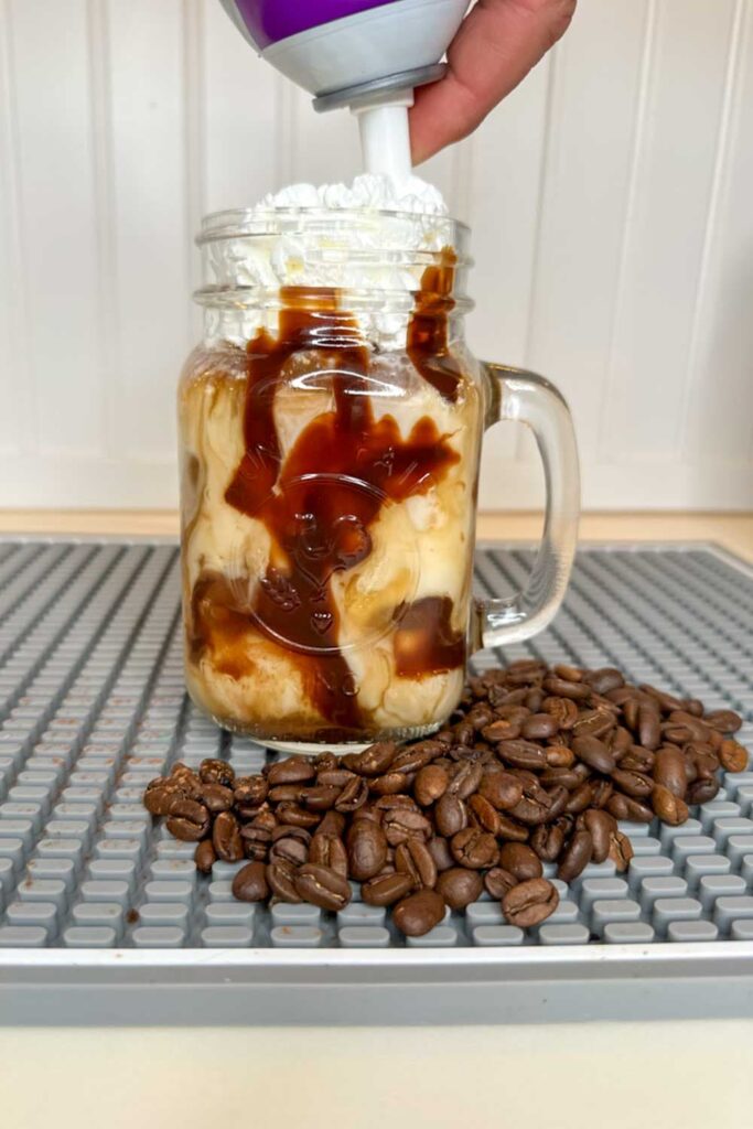 Adding whip cream to the iced coffee drink