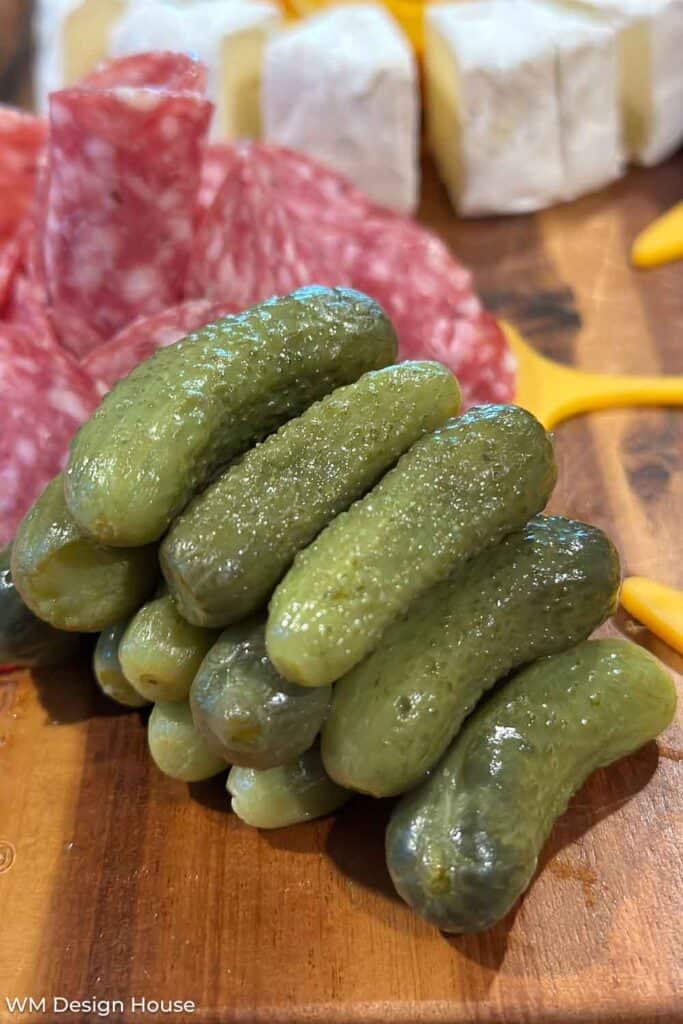 Adding pickles to a charcuterie board. 
