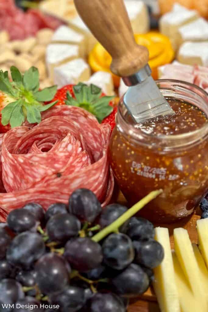 Fig jam, berries and a salami rose on a charcuterie board to serve with wine 