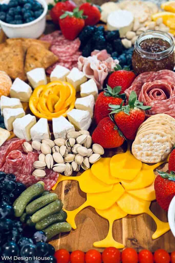 A charcuturie board with wine, cheeses, fruit, nuts and meats. 
