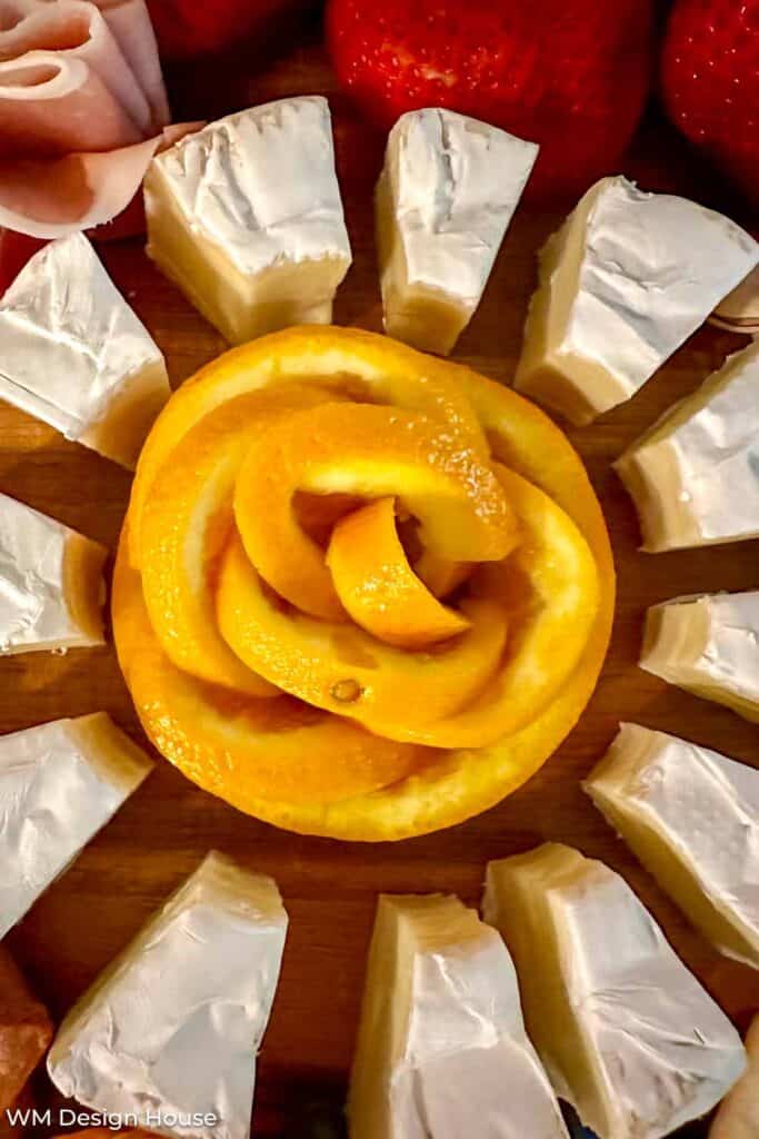 Brie cheese served with an orange flower in the center of a charcuterie tray 