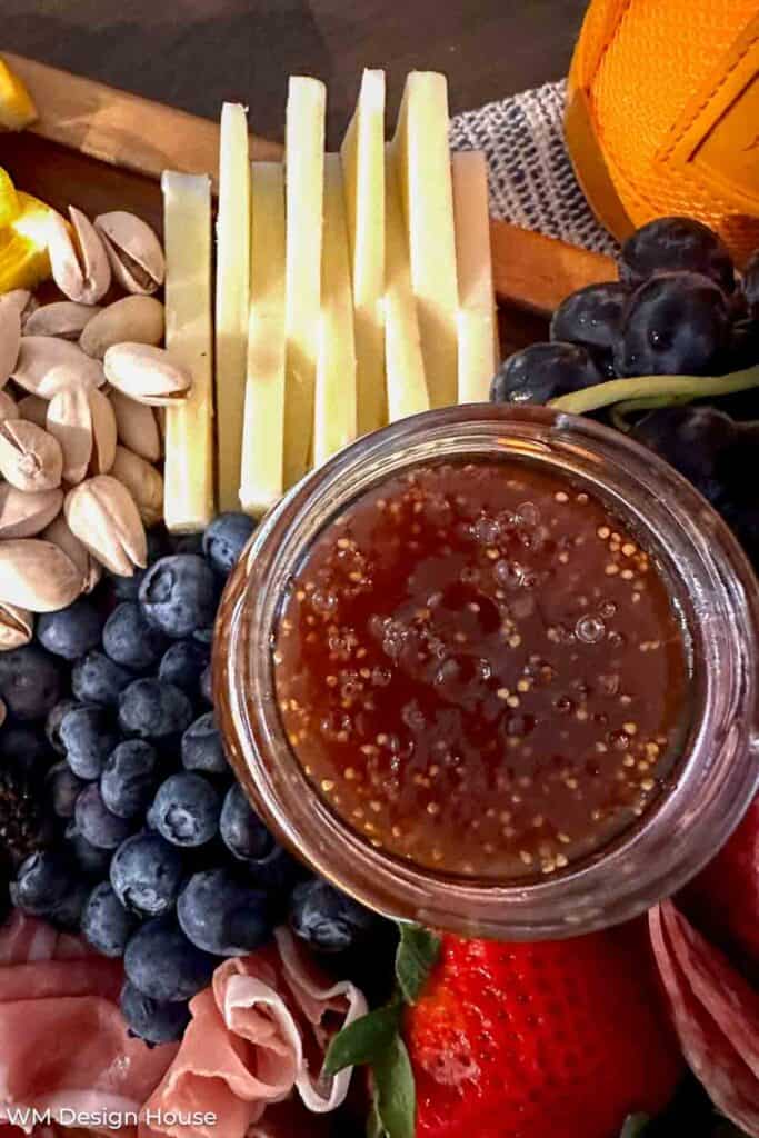 Fanned out white cheese on a charcuterie tray with grapes and fig jam 