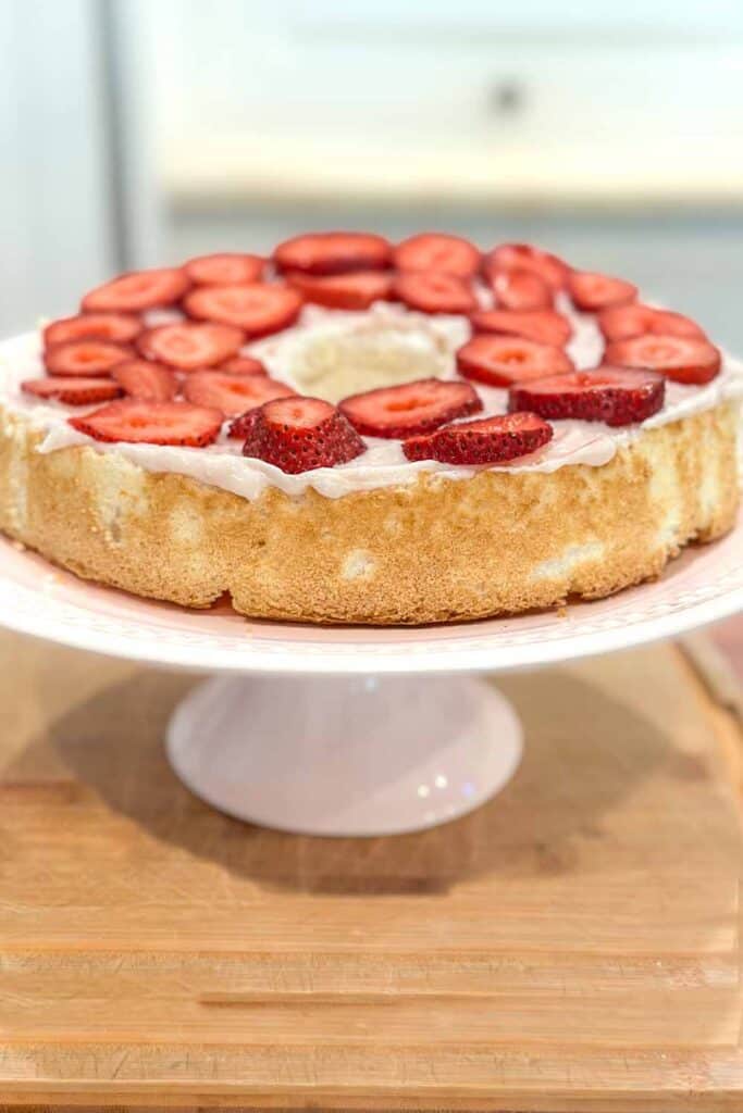 SIngle layer of angel food cake with a layer of cream cheese frosting and sliced strawberries. 
