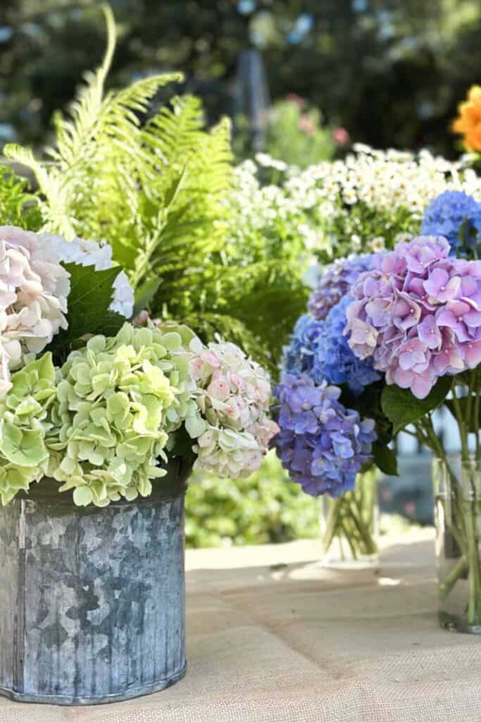 metal buckets filled with hydrangeas sitting on a table for a DIY flower Bar