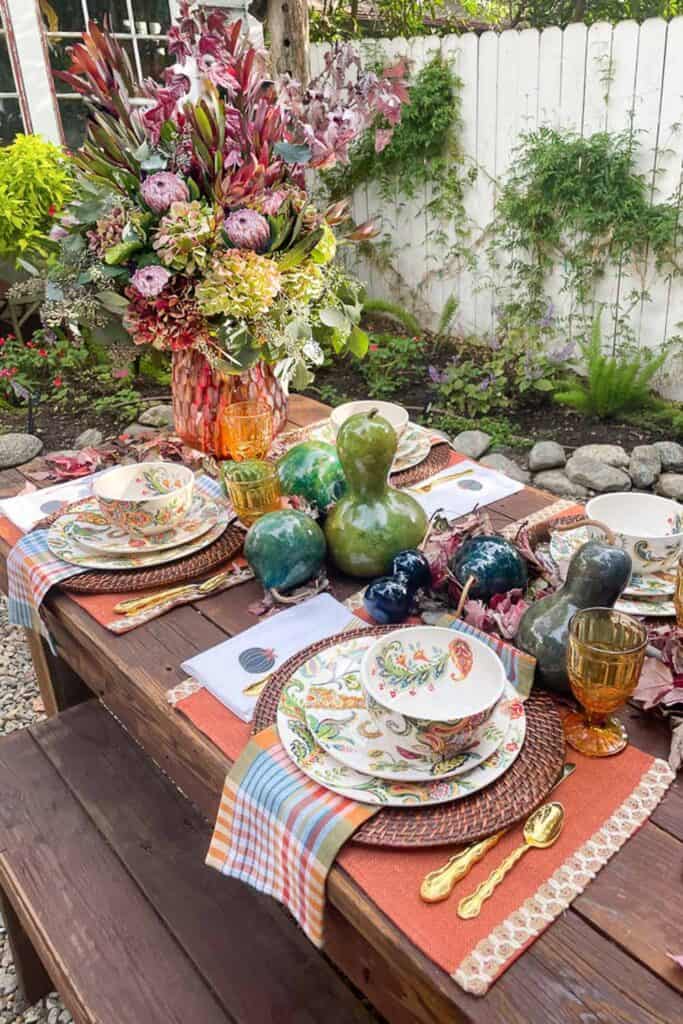 Potting garden table set for fall with gourds and fresh flowers 