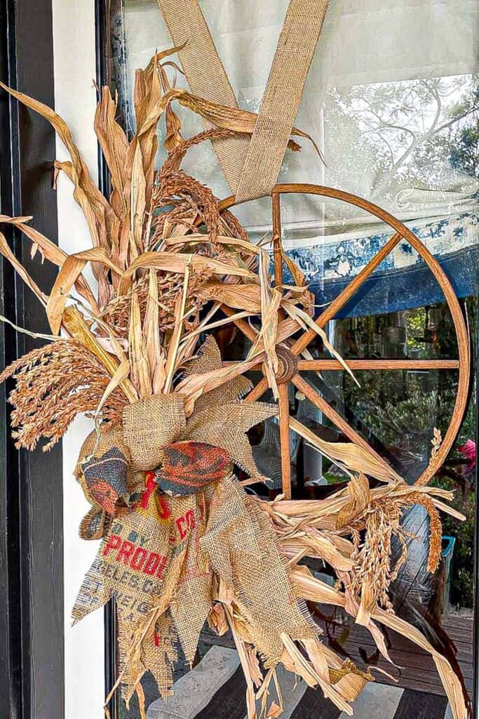 corn husk wreath on the front door mae out of a wagon wheel