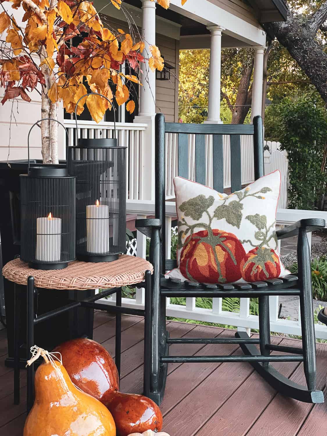 rocking chair with a fall throw pillow and front porch decorated for fall 