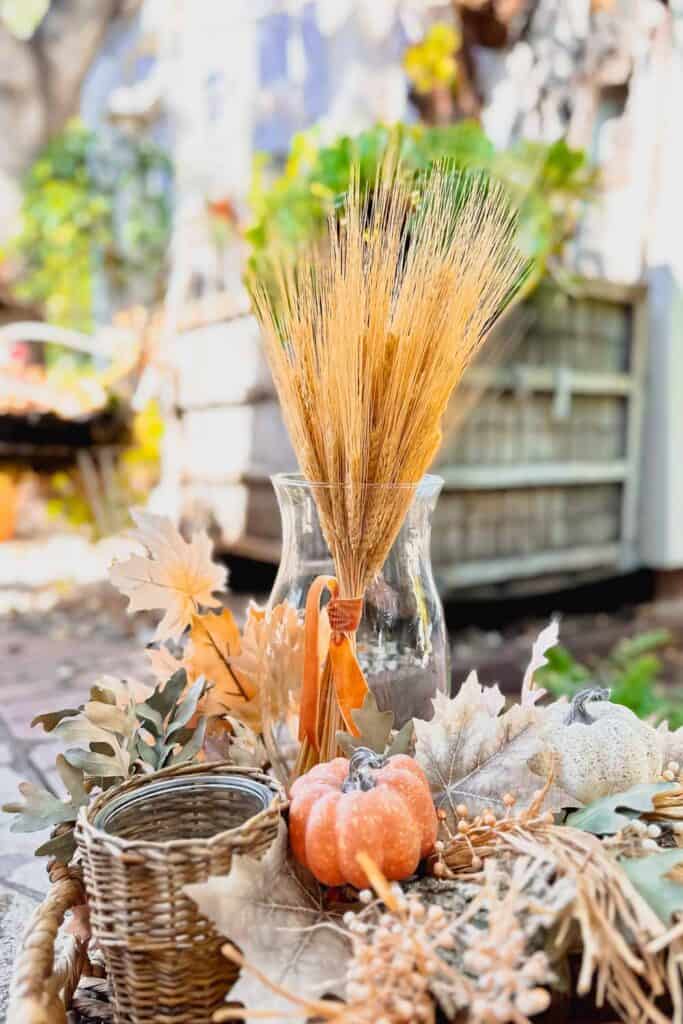 Fall DIY Projects- Bundle of wheat tied with a velvet ribbon and placed in a glass hurricane vase. 