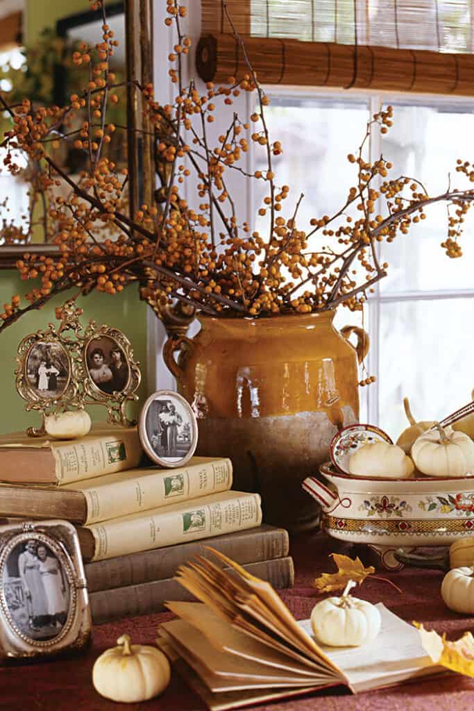 Autumn vignette  with pottery fillled with gold berries. old books and lots of small fall decor items 