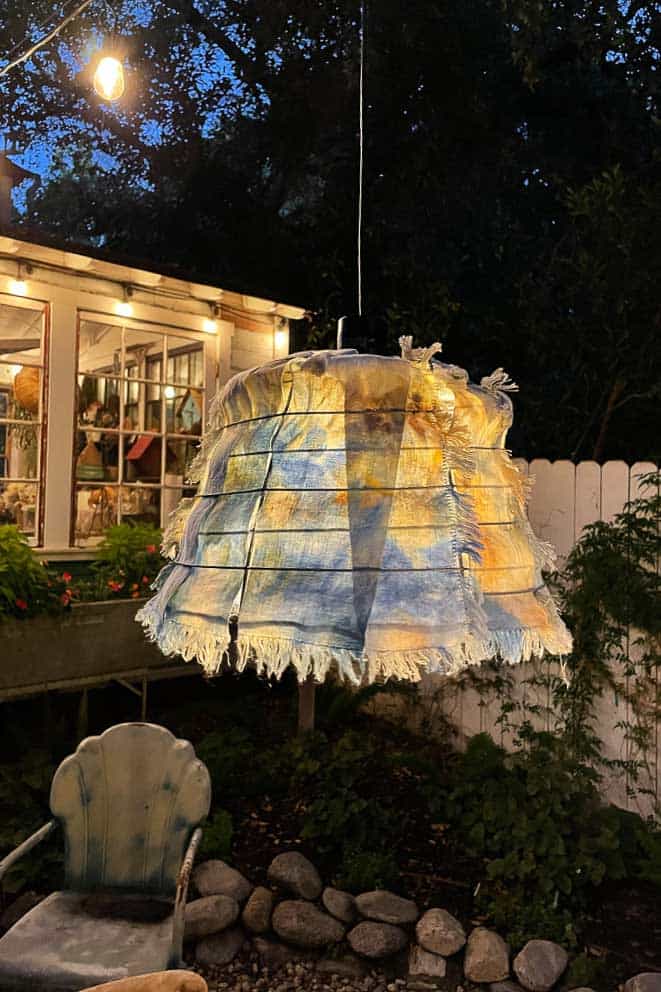 Outdoor fall tablescape- showing an outdoor light fixture that is made out of a garden basket with fabric woven through to look like a shade. 