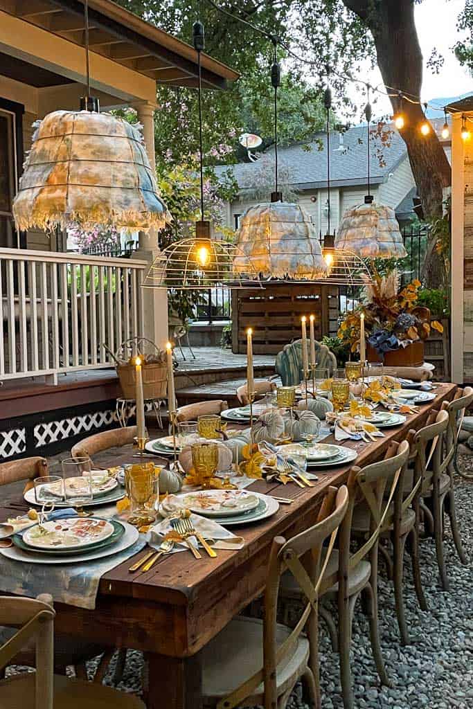 Outdoor fall tablescape - a view of the entire table set with blue and gold fall decorations. From dishes to pumpkins in an array of beautiful fall colors. 