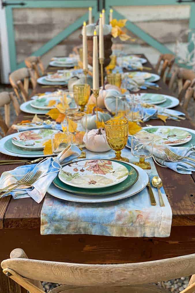 Table set with blue and gold ice-dyed linens . A table runner, placemats, and napkins make for a festive setting. 