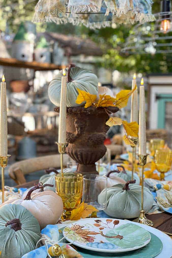 Outdoor taablescape with a rusty old urn for a centerpiece with a single velvet pumpkin sitting on the top. 