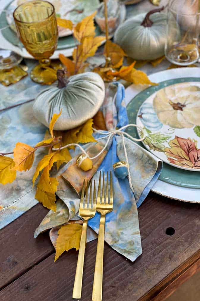 Fall outdoor tablescape with blue and gold linens , velvet pumpkins and acorn decorations