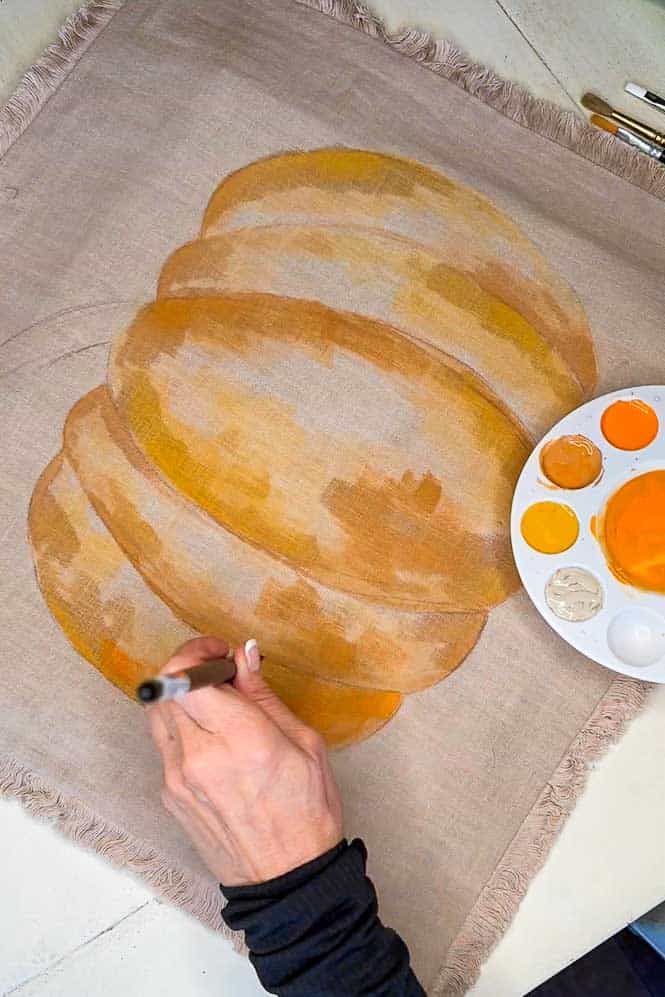 Hand painting a pumpkin onto a pillowcase.
