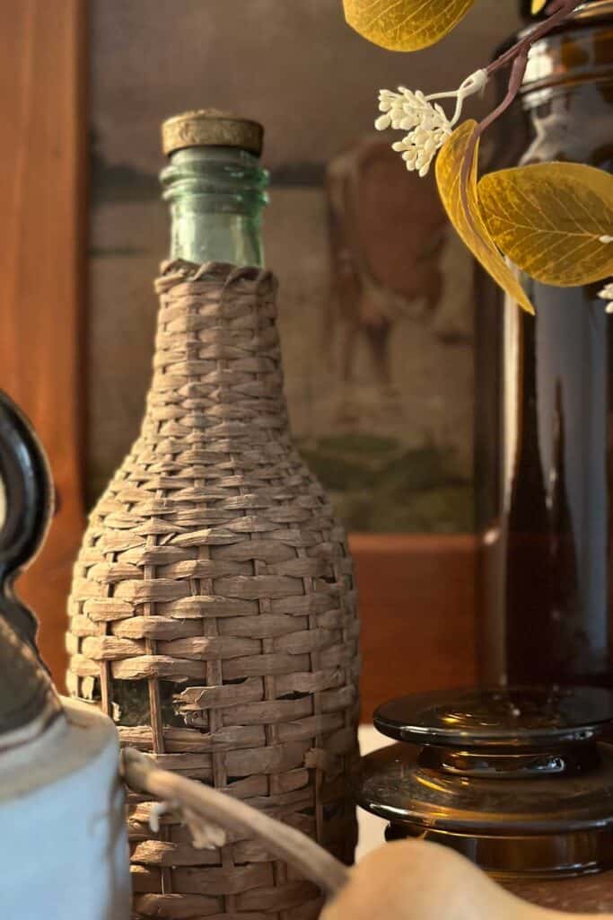 WICKER BOTTLE IN ITS NEUTRAL COLORS ADDS TEXTURE TO THE VIGNETTE. 