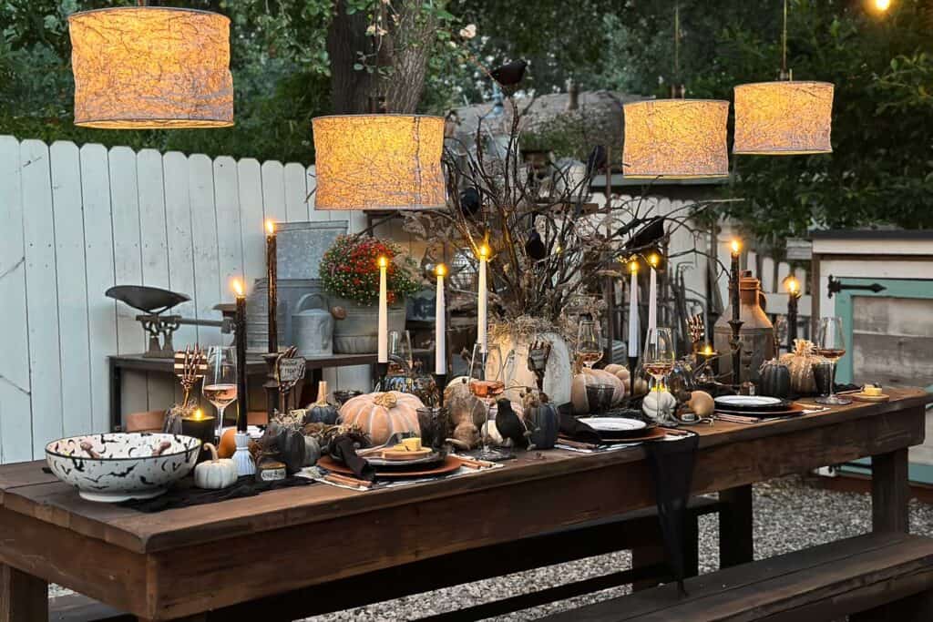 Halloween table with personalized DIY favors. Lampshades hanging over the table with lots of white candles, pumpkins, and other decor.