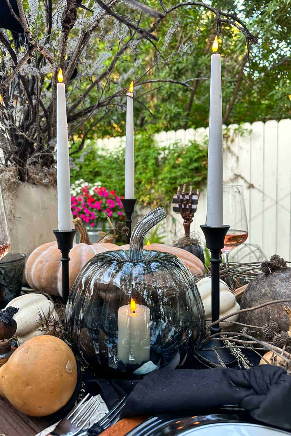 Black glass pumpkin with a battery operated candle inside decorating a Halloween tablescape 