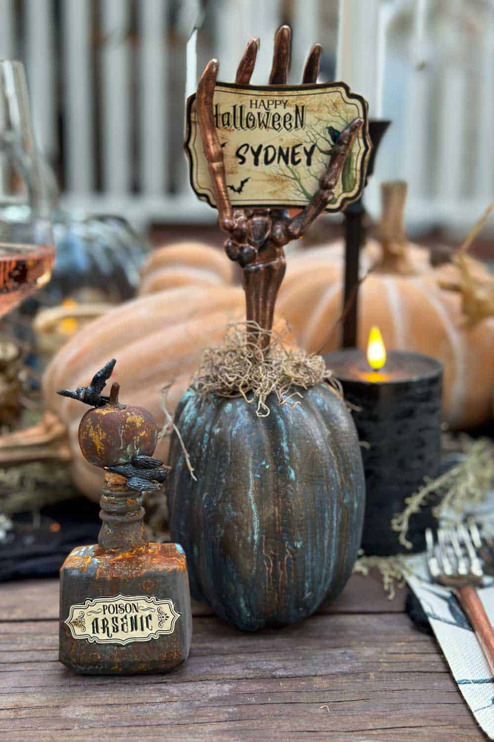 A name place card holder made out of a patina pumpkin with a skeleton hand and name card for a perfect Halloween table.