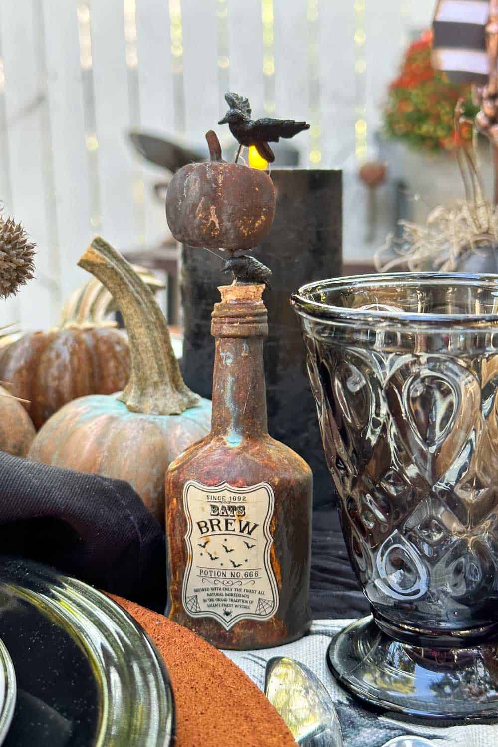 Halloween Tablescape- rusty old liquor bottle that has been painted and decorated with an apothecary label.