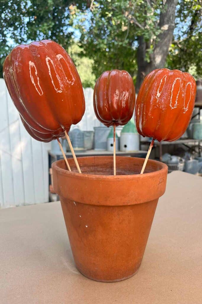 Foam pumpkins on skewers standing in a flower pot waiting for a coat of paint to dry.
