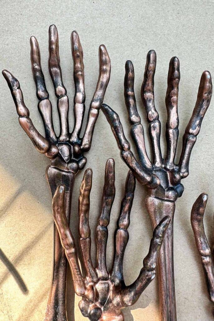 Three skeleton hands spray painted rose gold with a black paint rub over for a spooky look. 