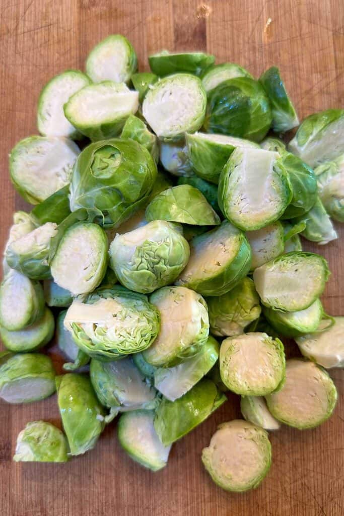 A pile of Brussels Sprouts cut in half on a cutting board. I was prepared to add to the cast iron pan to smoke the Brussel Sprouts.