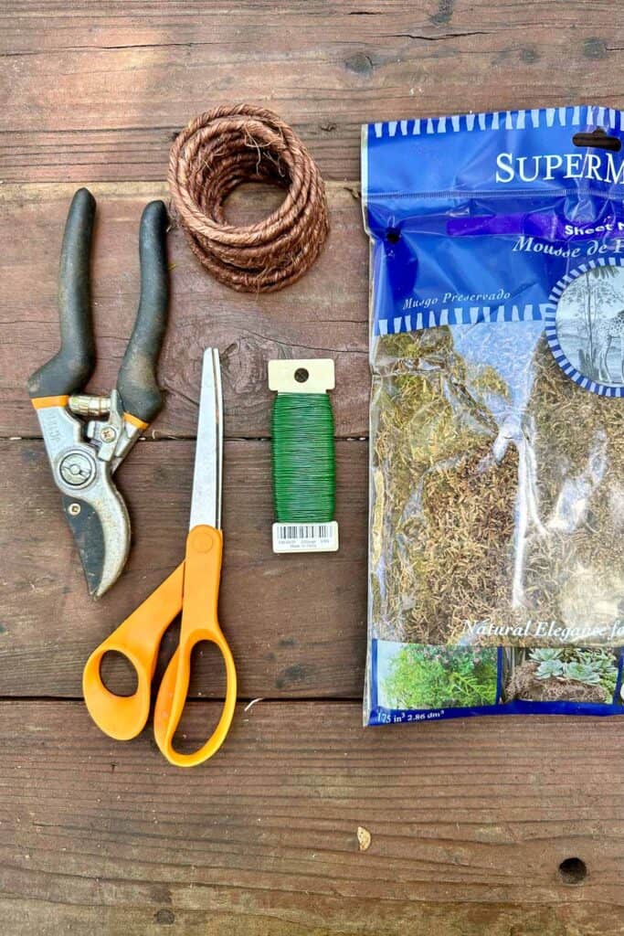 Tools needed to make a fall foraged wreath including scissors, wire, clippers and moss