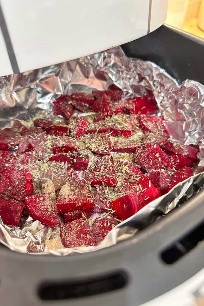 Roasted beets with seasonings ready to be cooked in the air fryer basket.