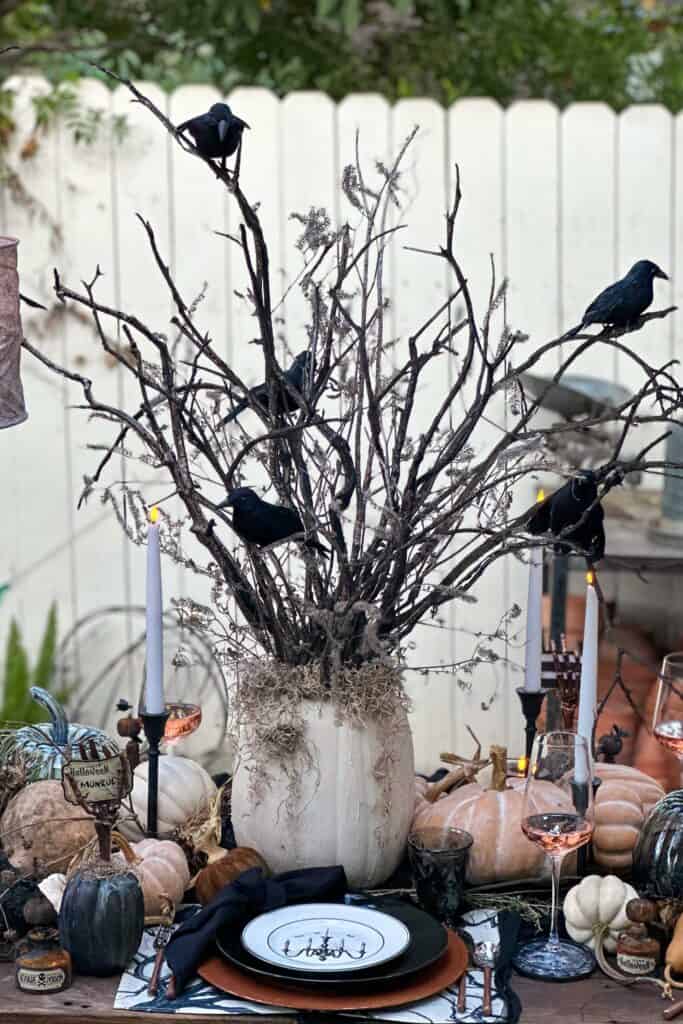 Elegant and spooky Halloween tree crafted out of tree branches and a large faux pumpkin 