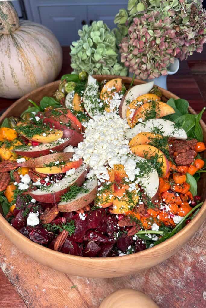 Close-up of a roasted vegetable salad served with carrots, beets, brussels sprouts, feta cheese, fresh dill and candied pecans.