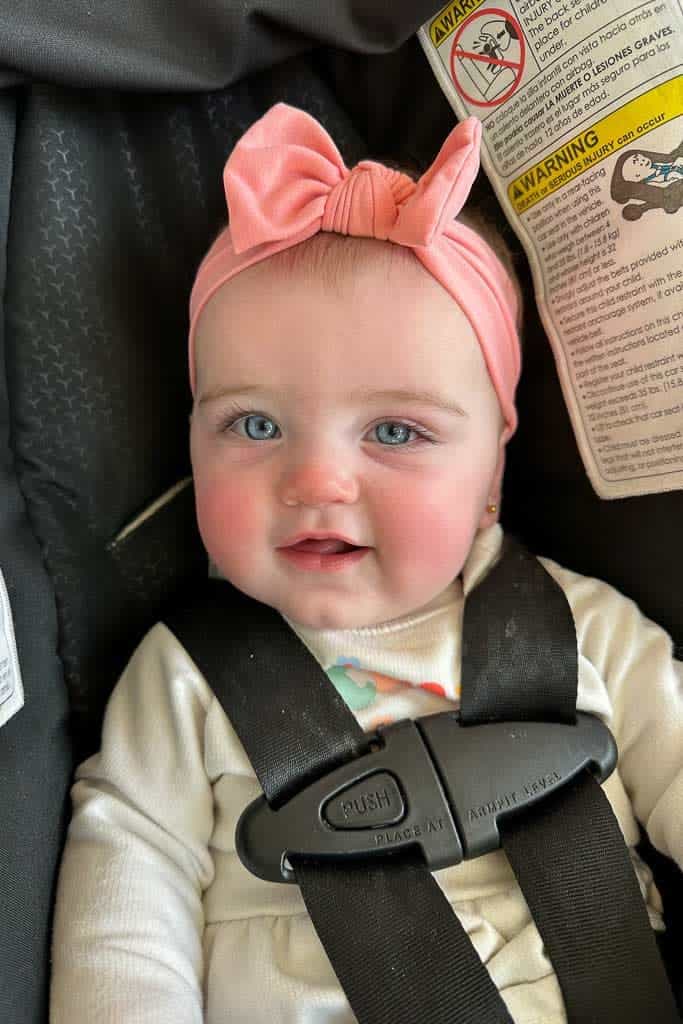 BABY LULU IN THE CAR SEAT WITH A PINK BOW IN HER HAIR. 