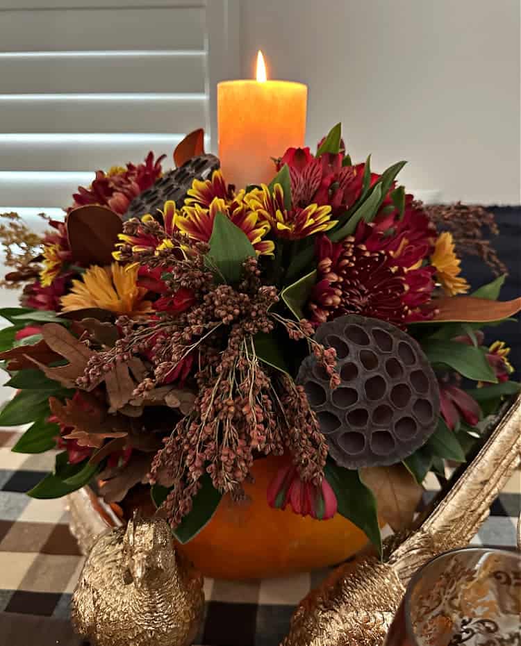 Floral arrangement with a candle made in a pumpkin.