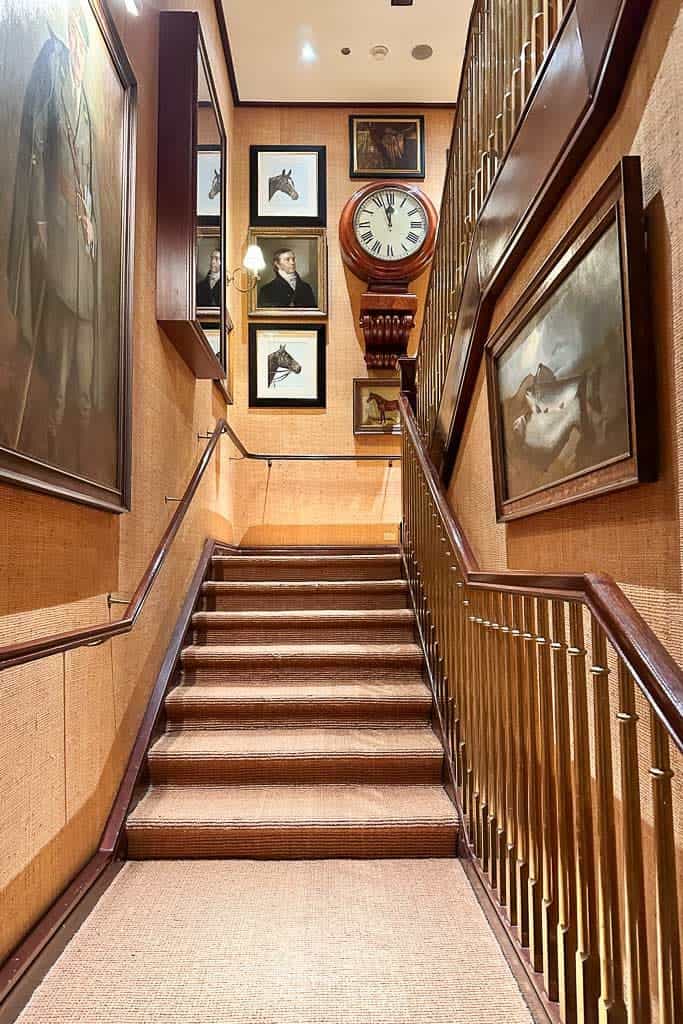 Staircase in the Ralph Lauren Store in downtown Chicago. The stairs and walls are covered with natural grasscloth. Pictures and clocks hang on the walls.  