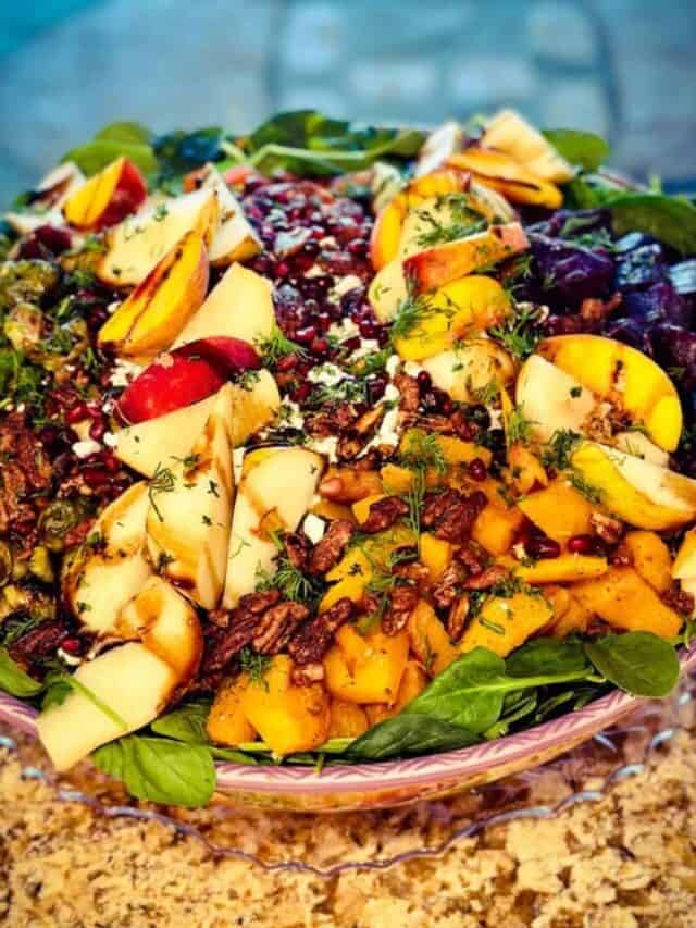 A beautiful bowl of salad, including fresh roasted vegetables and fresh fruit. This salad is topped with fresh dill, candies pecans, and pomegranate seeds.